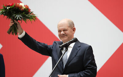 Olaf Scholz, top candidate for chancellor of the Social Democratic Party (SPD), holds a bunch of flowers after a press statement at the party's headquarter in Berlin, Germany, Monday, Sept. 27, 2021.  (AP Photo/Lisa Leunter)