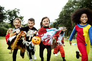 Little kids in costumes running to go trick or treating during Halloween.