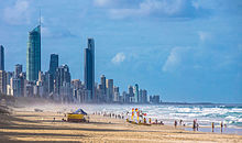 A beach populated by people; a city can be seen in the horizon