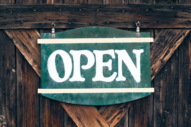 Green 'Open' sign attached to a wooden door