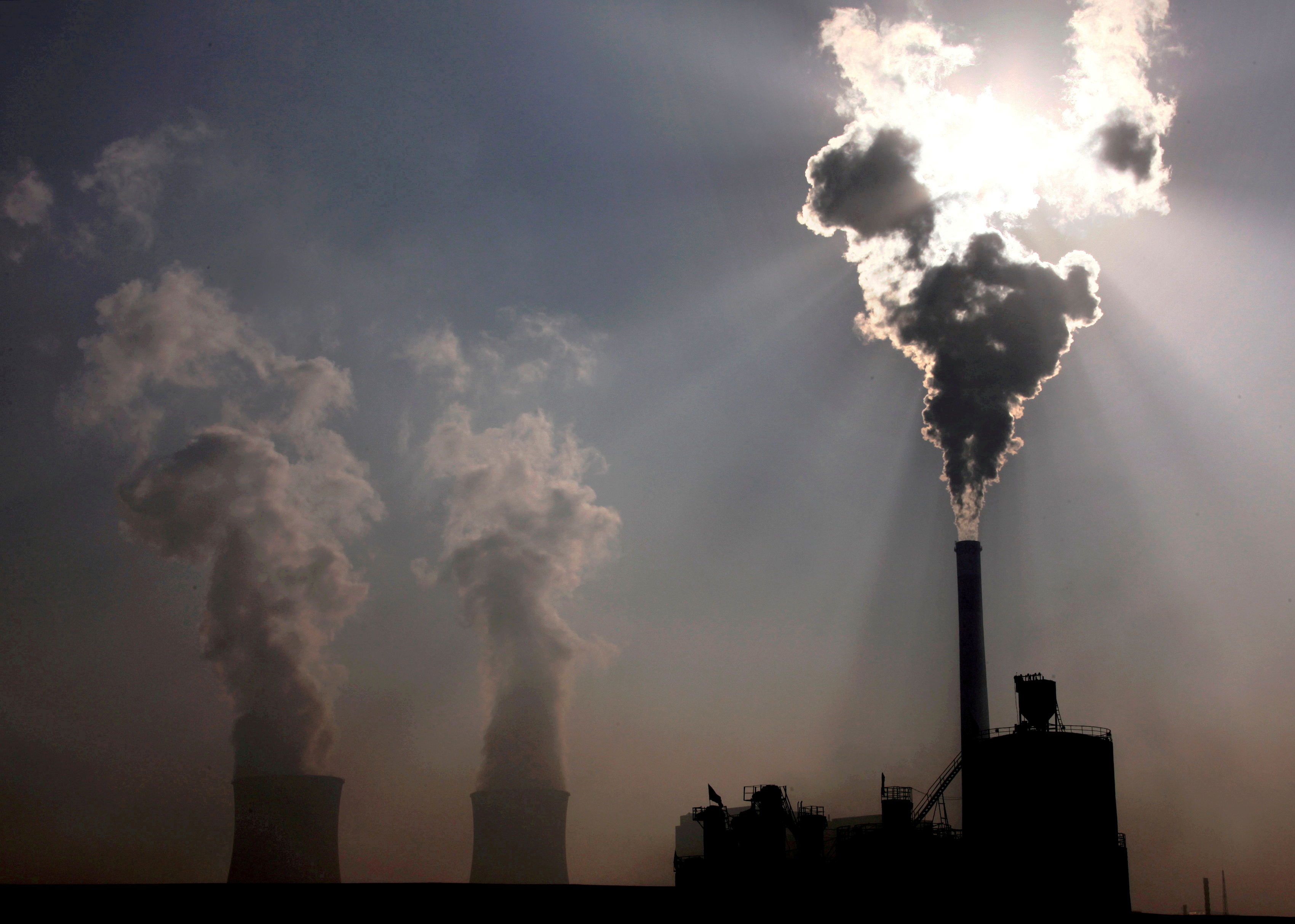 A coal-burning power plant can be seen behind a factory in the city of Baotou, in China's Inner Mongolia Autonomous Region, October 31, 2010.  REUTERS/David Gray/File Photo - RC2SYP9ETGNL