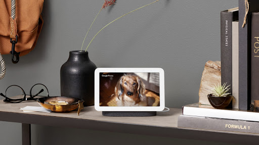 Nest Hub is located on a wooden table displaying pastel colors on screen and surrounded by pottery and tools.