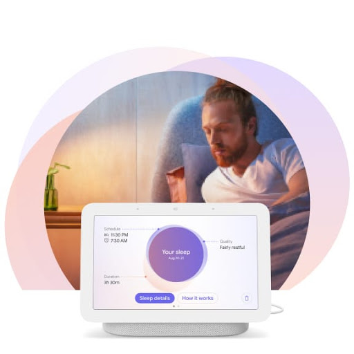 The man is sitting upright in bed and is turning toward his Nest Hub display at his bedside. It shows personalized insights about his sleep.