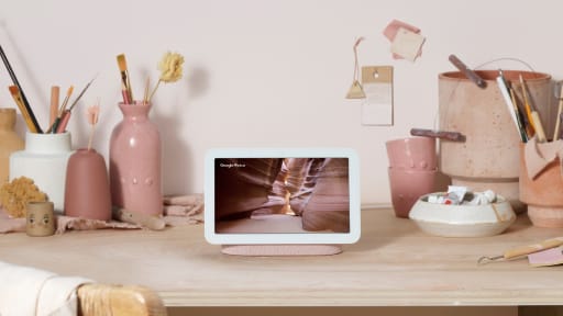 Nest Hub is located on a wooden table displaying pastel colors on screen and surrounded by pottery and tools.
