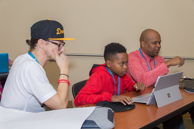 Zac Gordon watches a KidsCamp attendee work on his site.