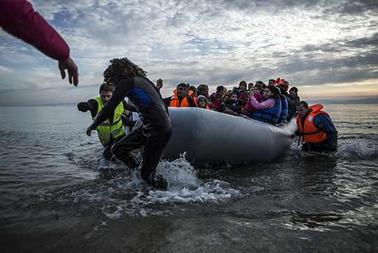 Migrants are helped by volunteers upon arrival on a dinghy to the Greek island of Lesbos