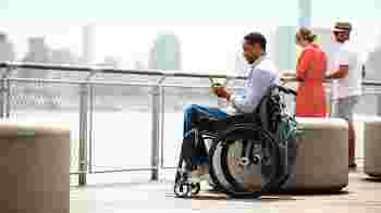 Man in wheelchair using Android on a pier.