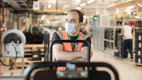 Amazon associate Mohanad wears a mask and safety vest inside an Amazon fulfillment center