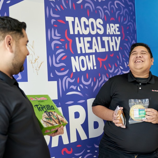 Ronald and Anthony hold their products in front of a Mr. Tortilla promotional sign.