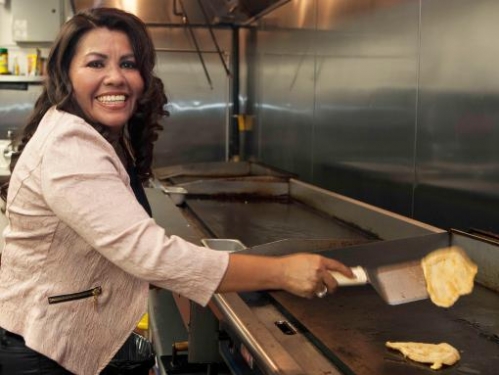 Escobar flipping pupusas at her restaurant