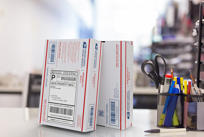 Priority mail boxes on table along with office supplies.