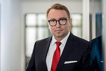 Male in business attire. White shirt, red tie, and jacket.