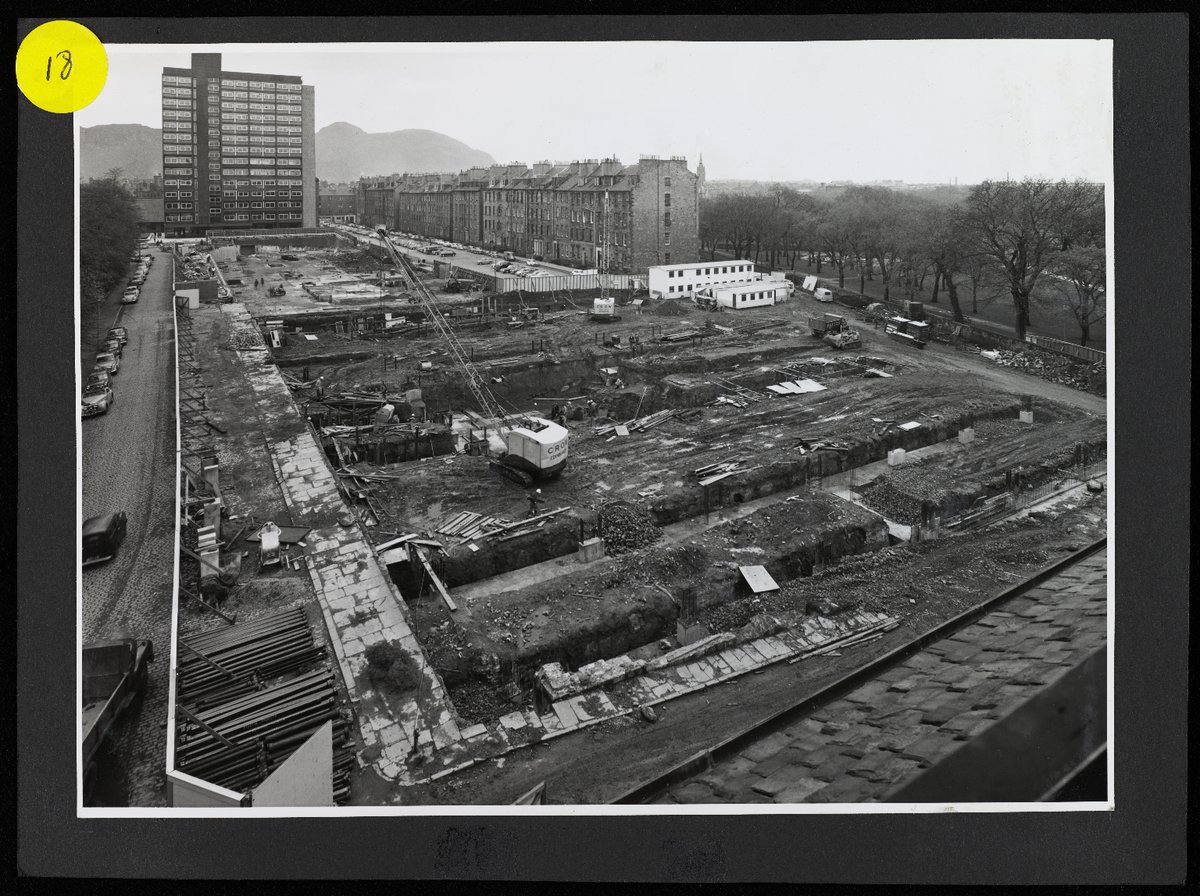 Black and white photograph of construction of Main Library from 1965-1967. In this photo the foundations are visible on the constructin site with Buccleuch Place, 40 George Square and Arthur's Seat in the background.