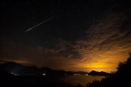 Sternschnuppe bei von unten erleuchteter Wolkendecke