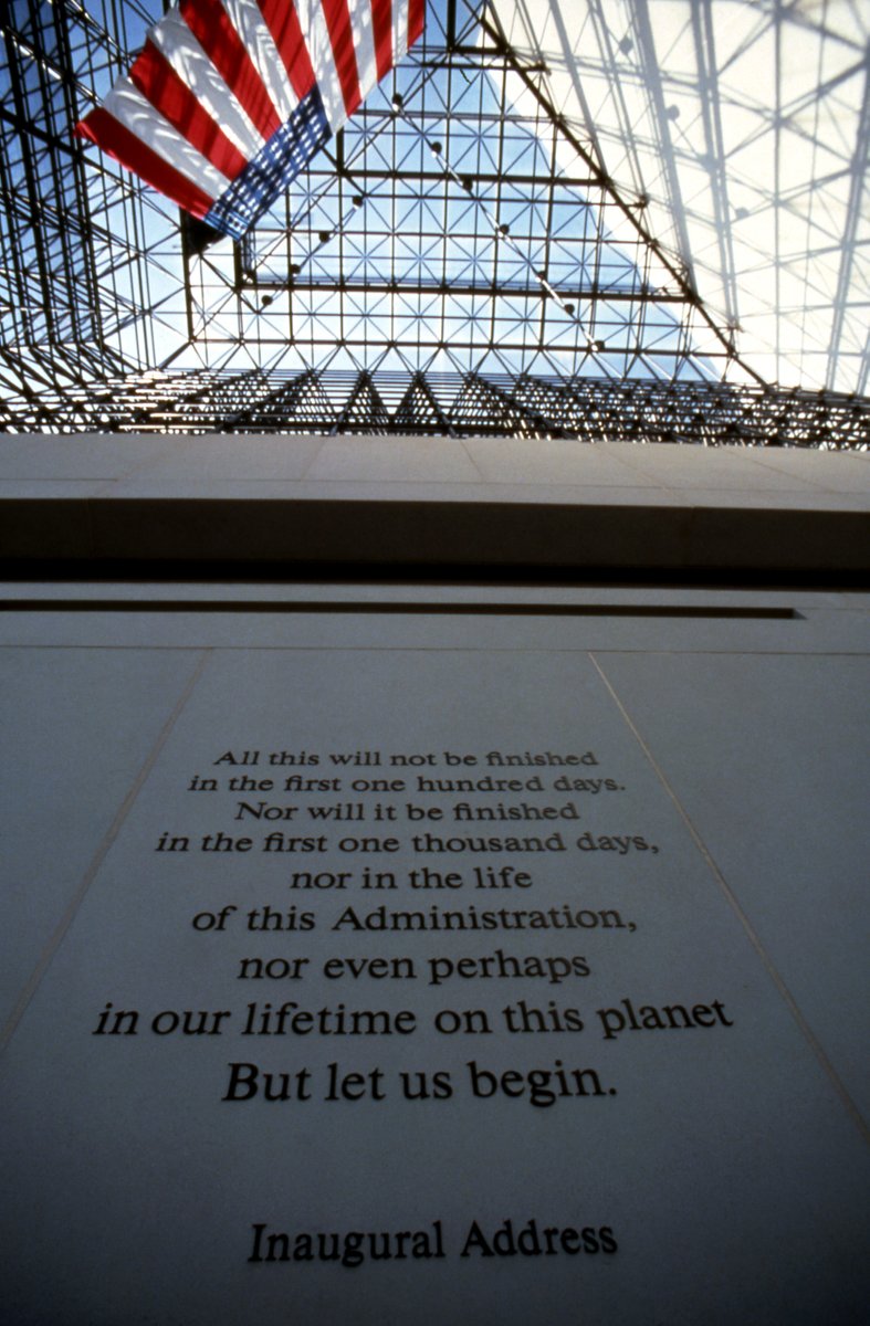 View of the wall up to the space frame inside the Pavilion of the Library. A very large American flag hands from the ceiling of the Pavilion. On the wall reads a line from President Kennedy's inauguration:
“All this will not be finished in the first one hundred days. Nor will it be finished in the first one thousand days, nor in the life of this Administration, nor even perhaps in our lifetime on this planet. But let us begin.”