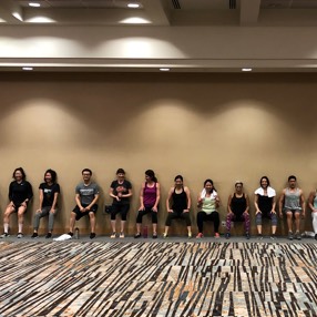 A row of employees doing coordinated squats against a wall