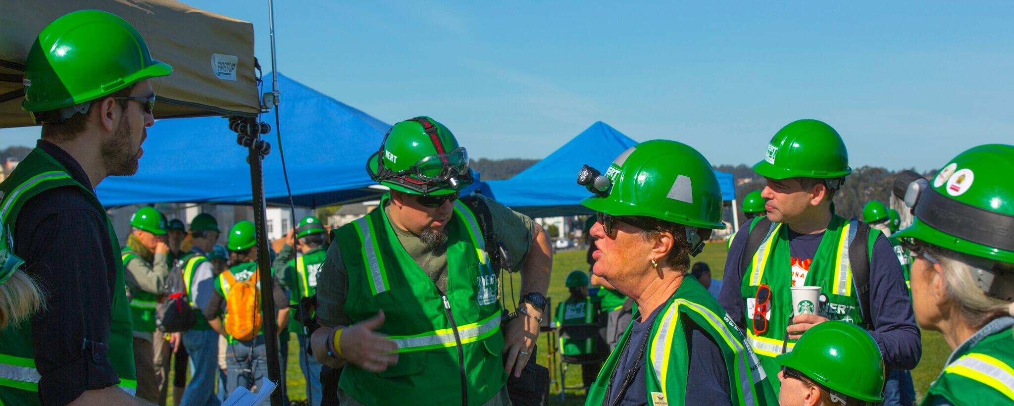 Six men and woman in green CERT vests and hard hats