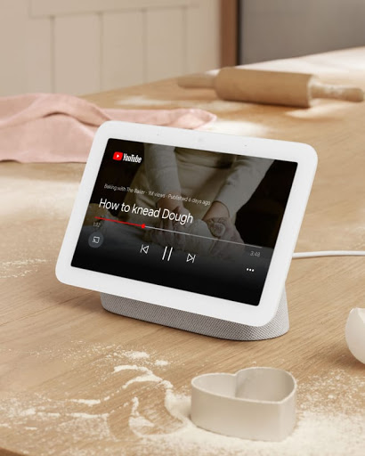 Nest hub on table with other cooking supplies in background.