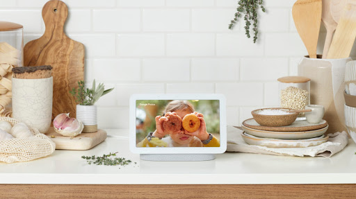 Nest Hub is located on a wooden table displaying pastel colors on screen and surrounded by pottery and tools.