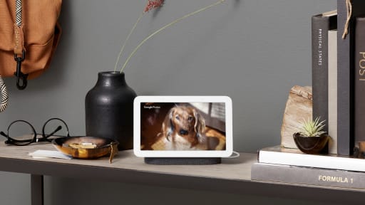 Nest Hub is located on a wooden table displaying pastel colors on screen and surrounded by pottery and tools.