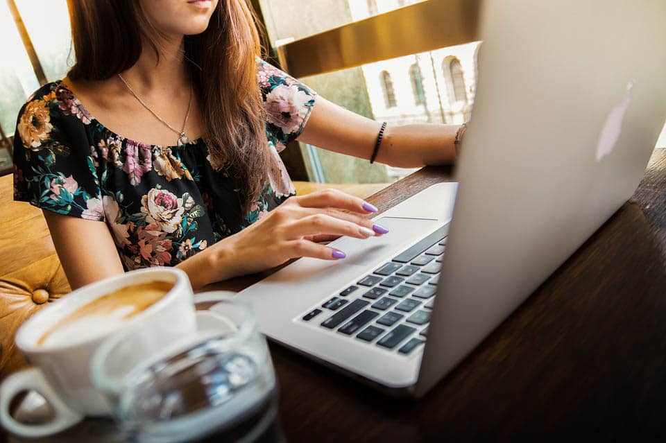 Woman in coffee shop on laptop - blogging