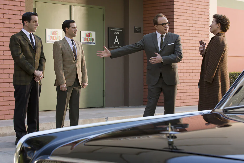 Actors Emma Thompson (as P.L. Travers), Jason Schwartzman (as Richard Sherman), Bradley Whitford (as Don DaGradi), and B.J. Novak (as Robert Sherman) on a sidewalk talking in the movie "Saving Mr. Banks".