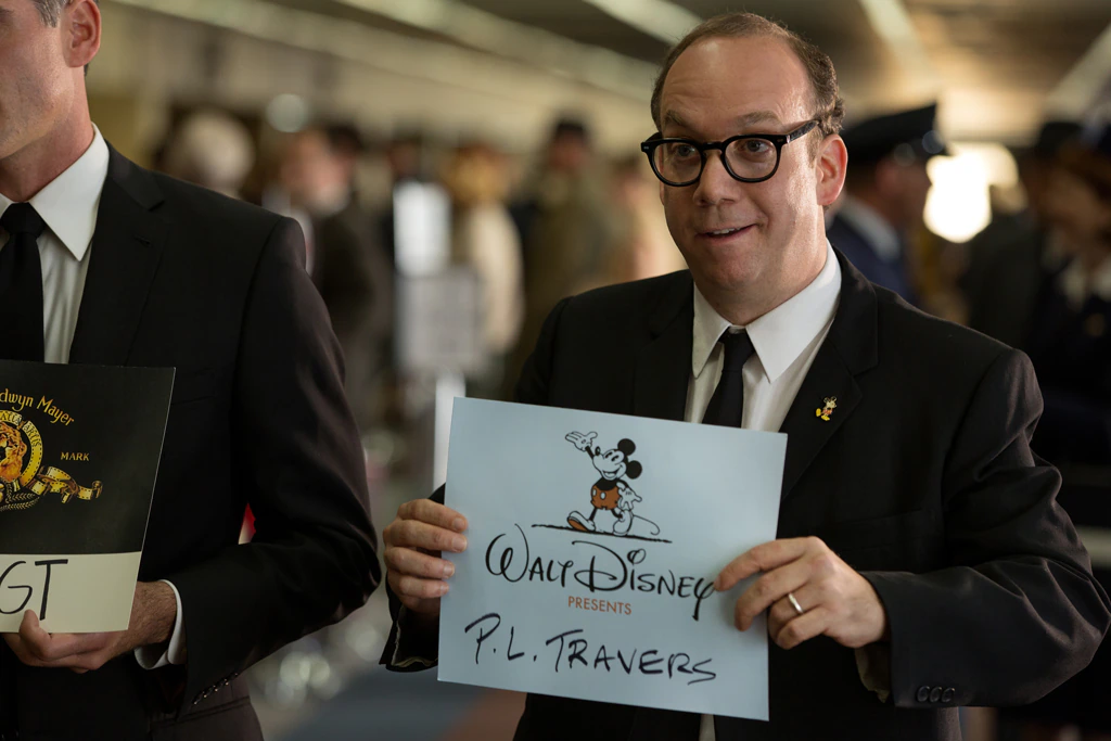 Actor Paul Giamatti as Ralph holding a Walt Disney sign with P.L. Travers written on it in the movie "Saving Mr. Banks".