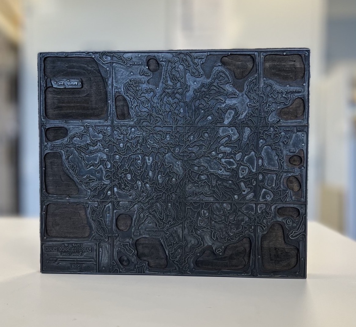 Metal printing plate map of Barro Colorado Island. It is standing upright on a table.