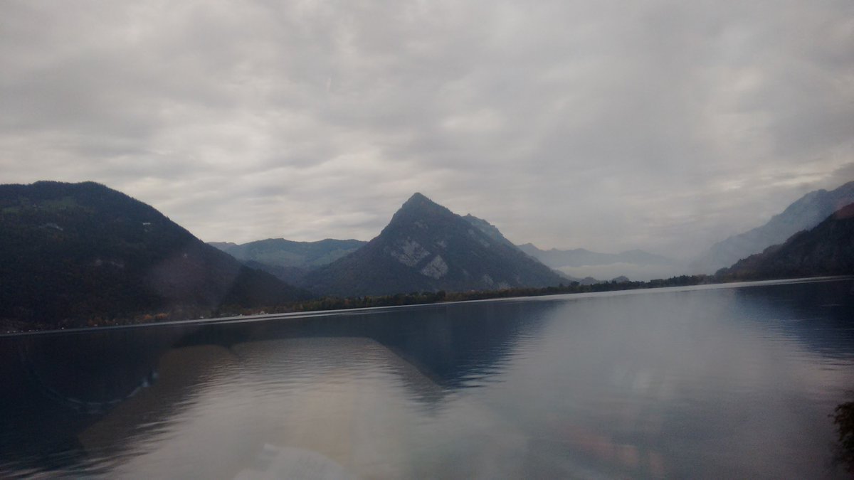 A gloomy looking lake with cloud cover and mountains in the back.