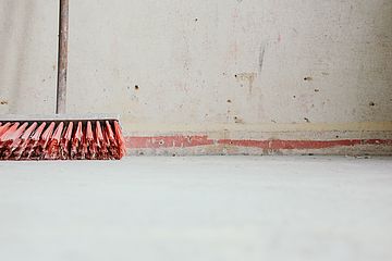 Low shot of floor with a wall. Sweeping brush is leaning to wall.