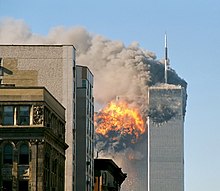 Two tall, gray, rectangular buildings spewing black smoke and flames, particularly from the left of the two.