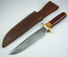 Large knife with polished wooden handle, lying next to a leather sheath