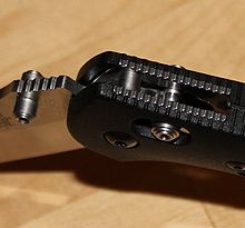 Close-up of the pivot joint of a folding knife, showing locking barrel inserted through holes in the handle