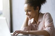 Beautiful young woman smiling and looking at laptop screen.