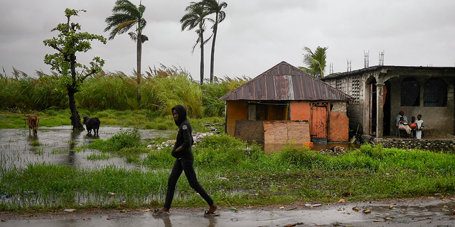 A man walks along a road in a slightly flooded area the morning after Tropical Storm Grace swept over the area in Trou Mahot, Haiti, Tuesday, Aug. 17, 2021, three days after a 7.2-magnitude earthquake. 