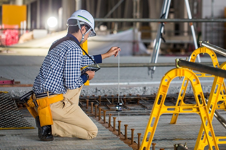 Construction worker takes digital measurements on a construction site