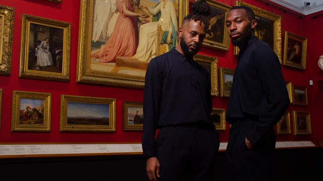 Two dancers stood in a red gallery