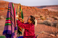 Elderly Navajo woman weaving a traditional native American blanket in the desert.