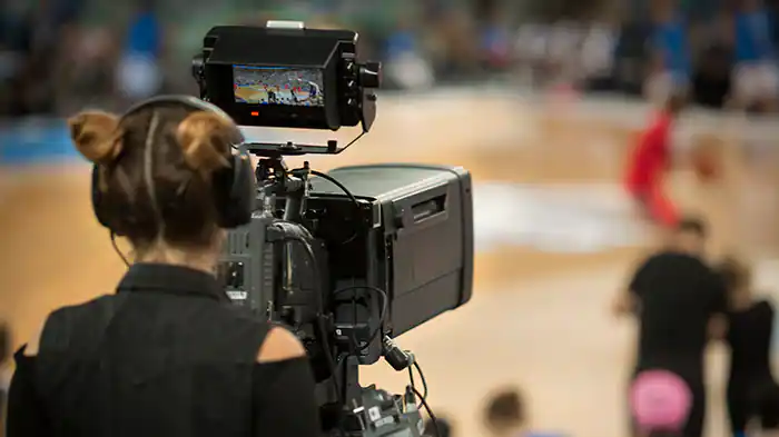 Female camerawoman shooting basketball game at Arena Stozice, Ljubljana, Slovenia.