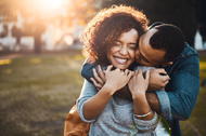 African american couple embracing effecionately outdoors in a park.