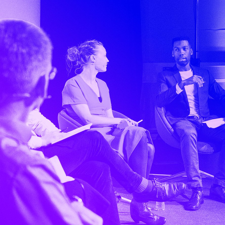 A photograph of the Governing AI panel on stage at MozFest 2019, with Xavier Harding charing the discussion.