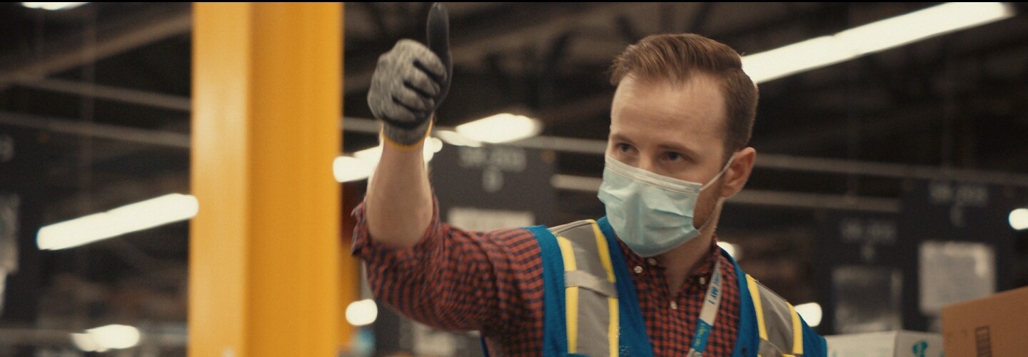 Amazon employee with thumb up and wearing mask