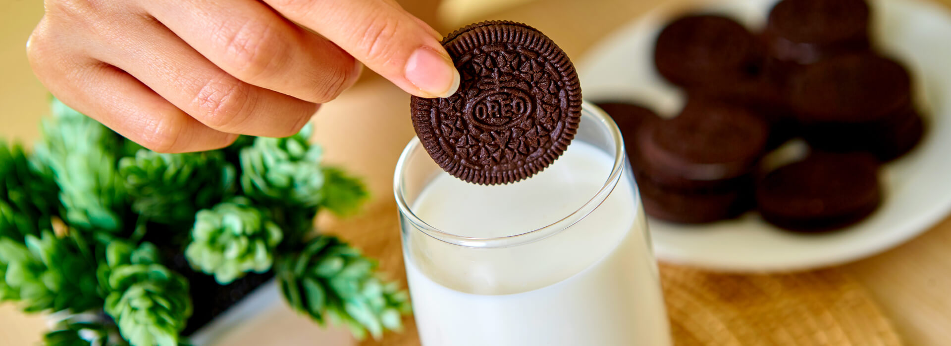 Person dunking an Oreo cookie into a glass of milk. 