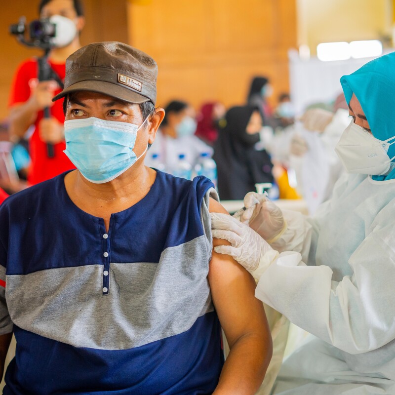 An Indonesian man is being vaccinated by a nurse in a vaccination centre