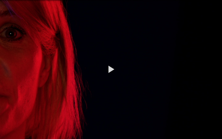 Die rot angeleuchtete linke Gesichtshälfte von Dominika Szope vor schwarzem Hintergrund.