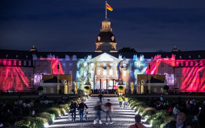 Foto eines bunten Projection Mappings bei Nacht auf dem barocken Karlsruher Schloss.