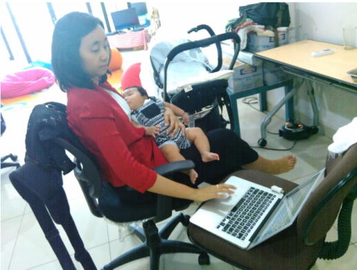 Annisa menggendong bayi sambil bekerja menggunakan laptop