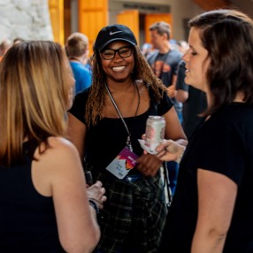 Three female-presenting employees talking and laughing at a company gathering in Whistler, Canada