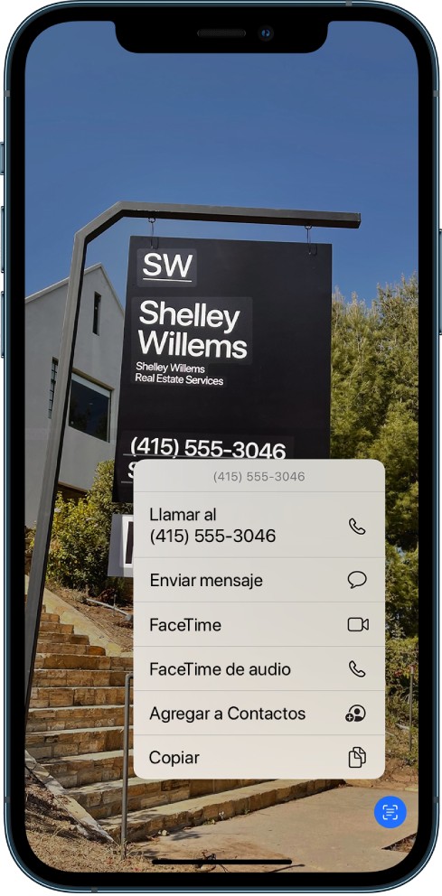 Una foto abierta en toda la pantalla. Dentro de la foto hay un letrero que incluye texto y un número telefónico. El número telefónico se selecciona y se muestran las siguientes opciones en pantalla: Llamar, Enviar mensaje, FaceTime, FaceTime de audio, Agregar a Contactos y Copiar.