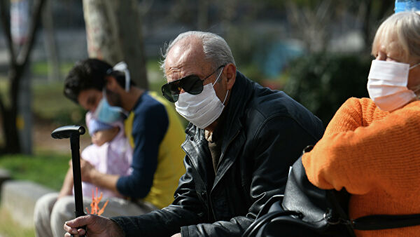 Люди, одетые в защитные маски, около больницы AHEPA